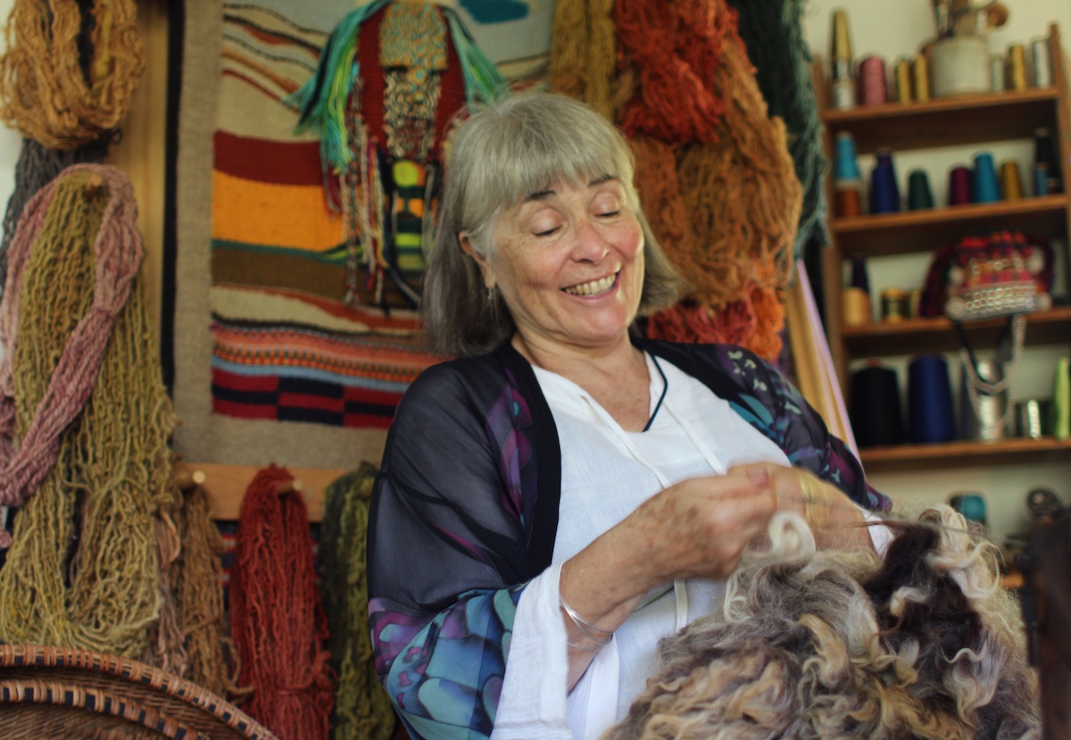 smiling woman spinning yarn on a spinning wheel